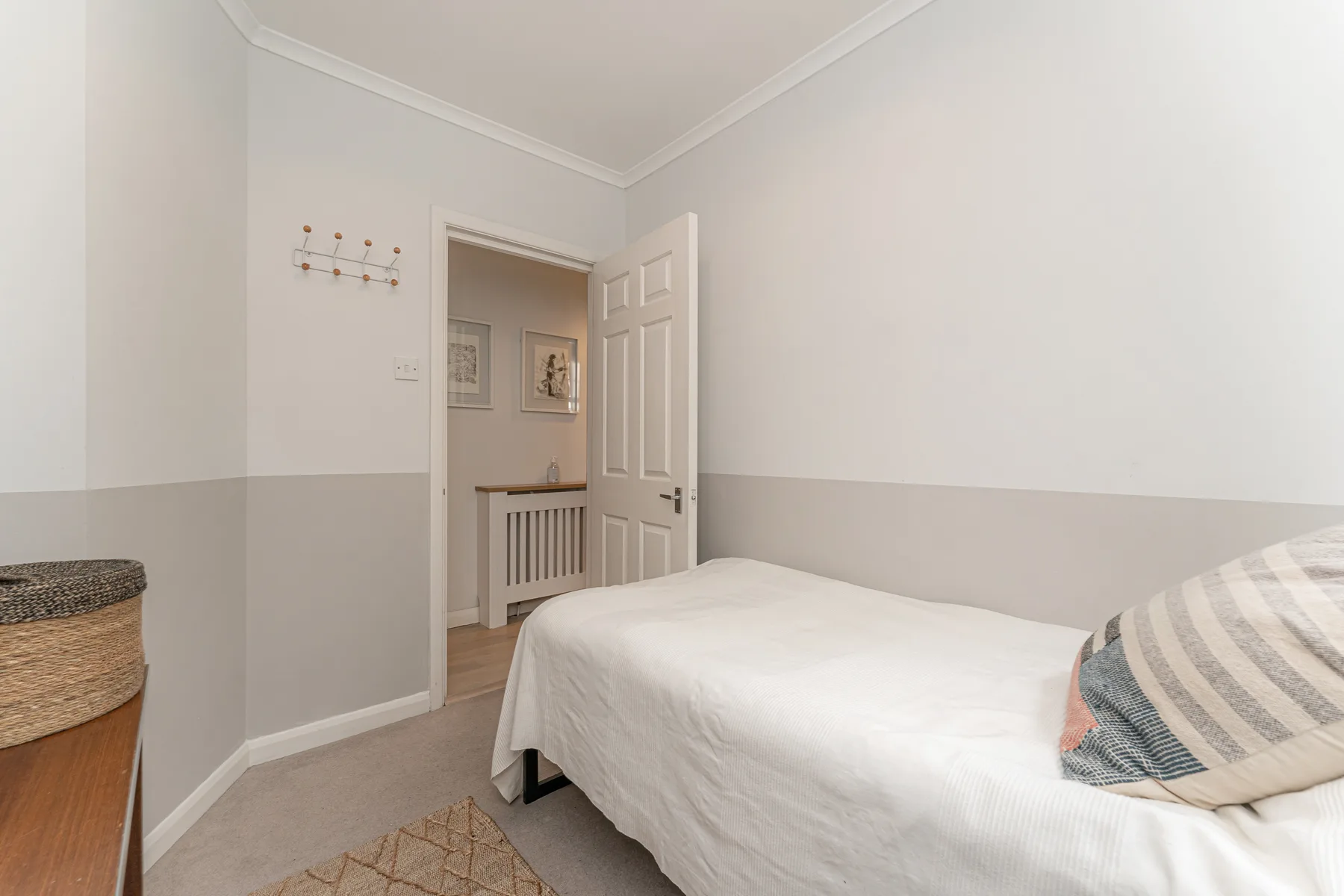 Un dormitorio con una cama, un cojín a rayas y una puerta abierta.
