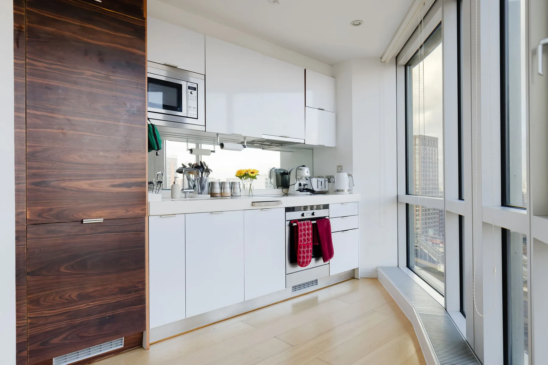 A bright modern kitchen with white cabinets and large windows.