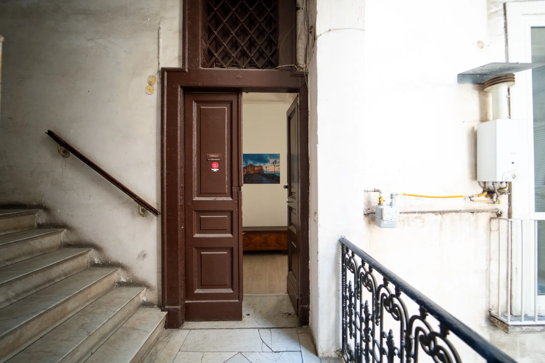 Una escalera con una puerta marrón abierta que da a una habitación.