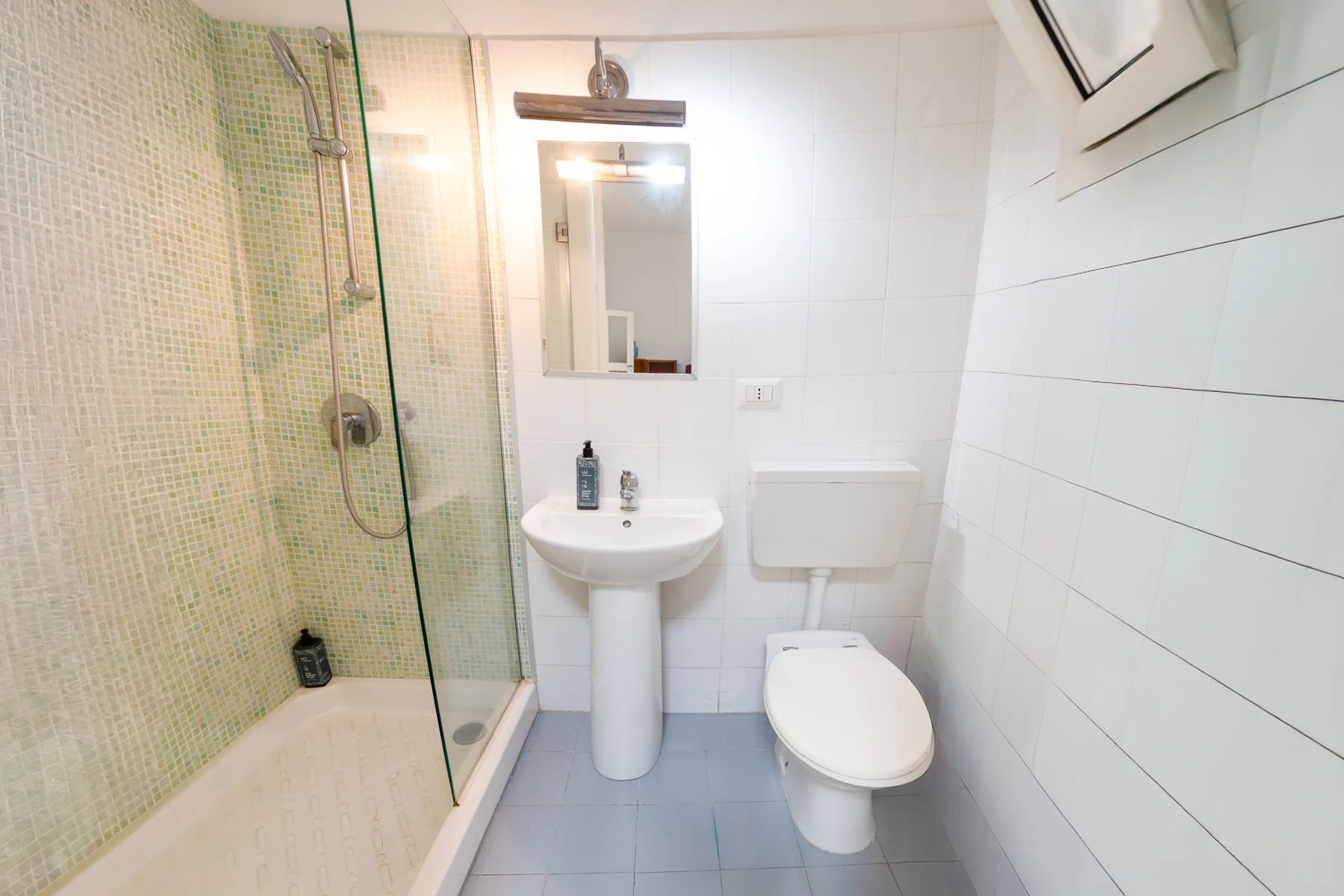 Un baño alicatado con ducha, lavabo e inodoro.