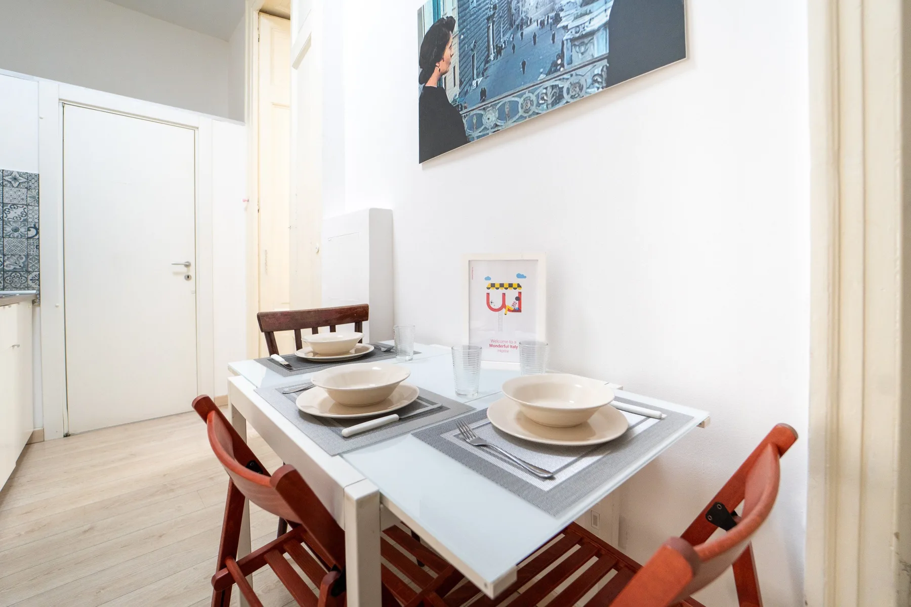 Un comedor luminoso con la mesa puesta y sillas rojas.
