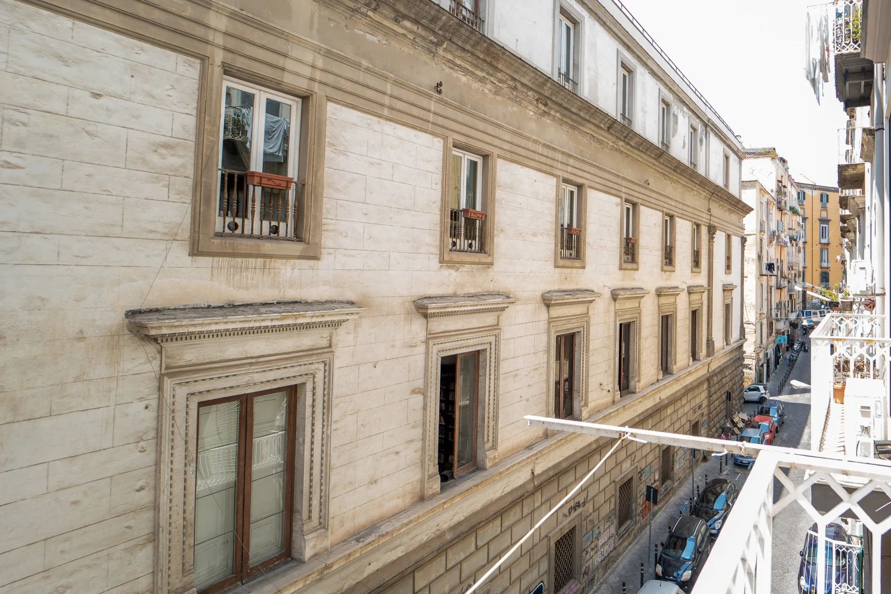 La fachada de un edificio de piedra con filas de ventanas junto a una calle estrecha.