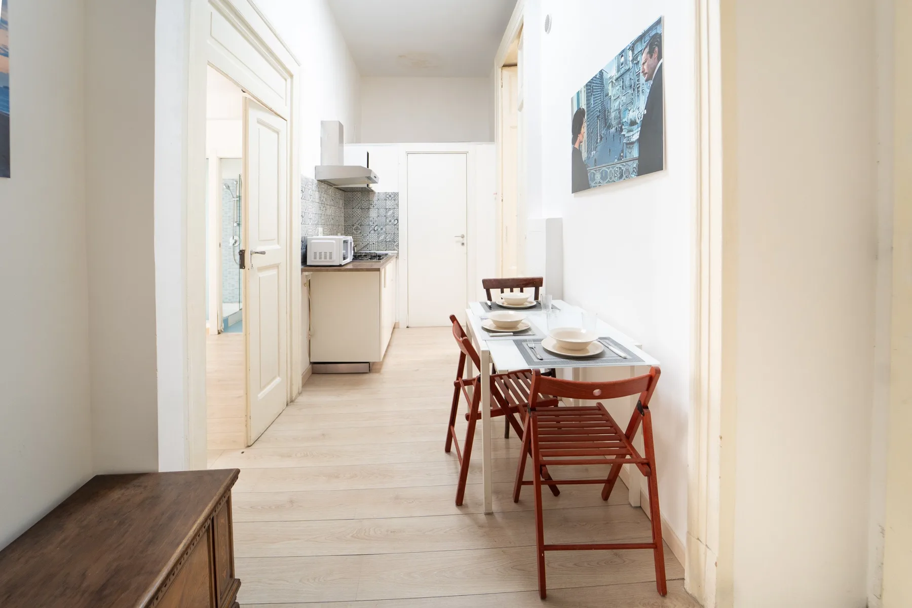 Un comedor luminoso con una mesa estrecha y sillas junto a una cocina compacta.