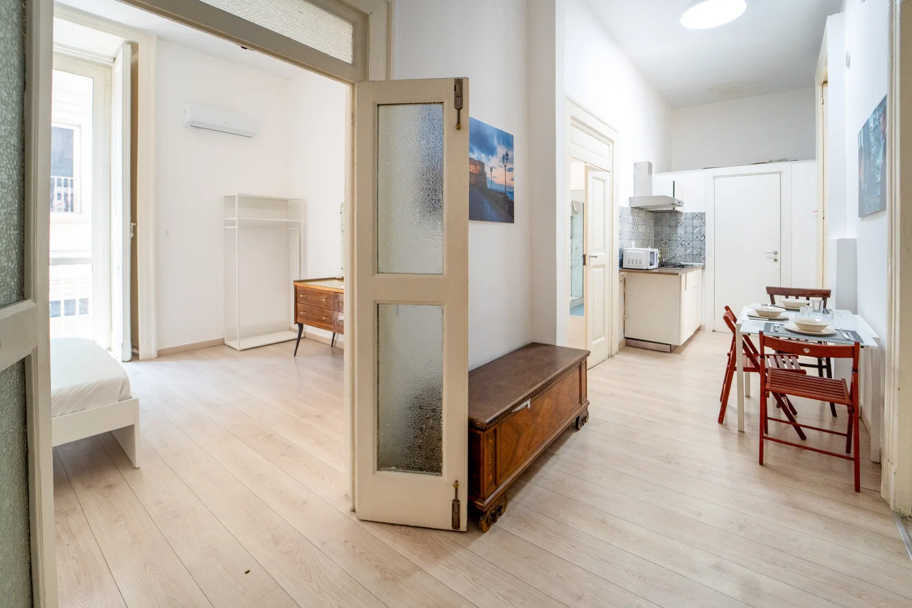 Una habitación luminosa y abierta con mesa de comedor, cocina y mueble de madera.