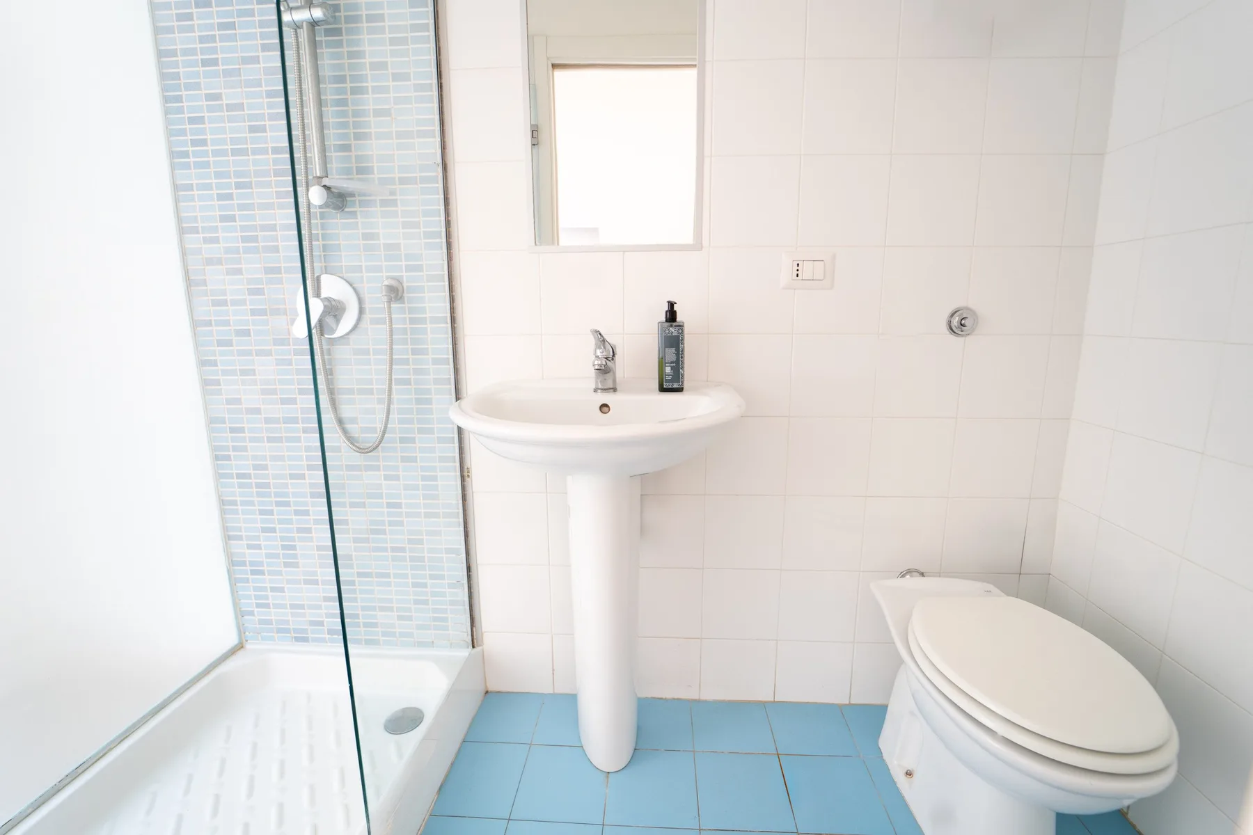 Un baño alicatado con ducha, lavabo e inodoro.