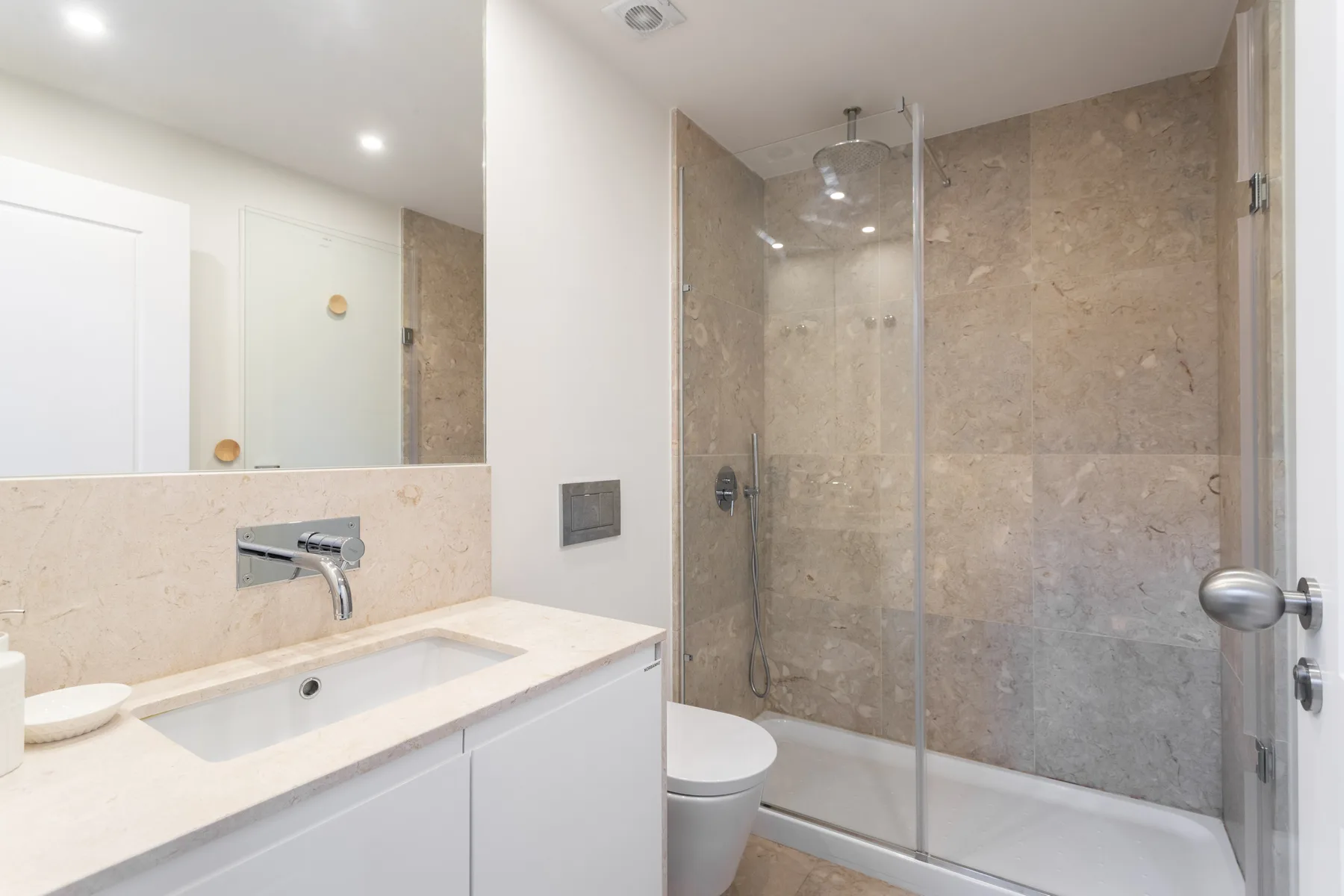 A bathroom with a sink, toilet, and glass shower.