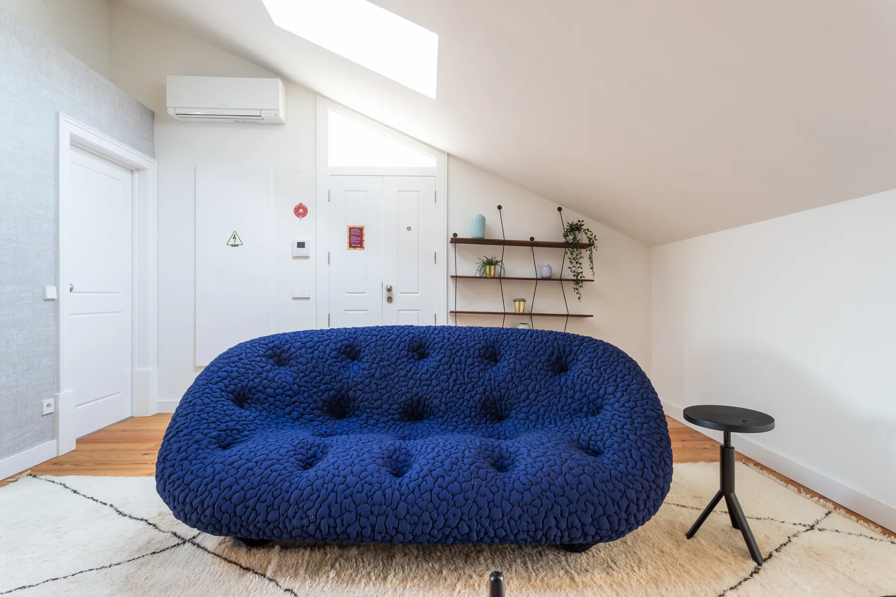 A bright living room features a blue sofa and a small side table.