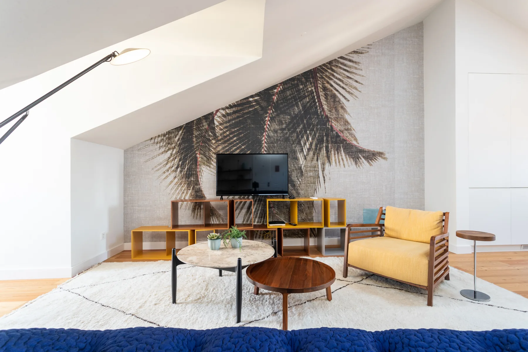 Living room with seating, a television, and a large palm mural.