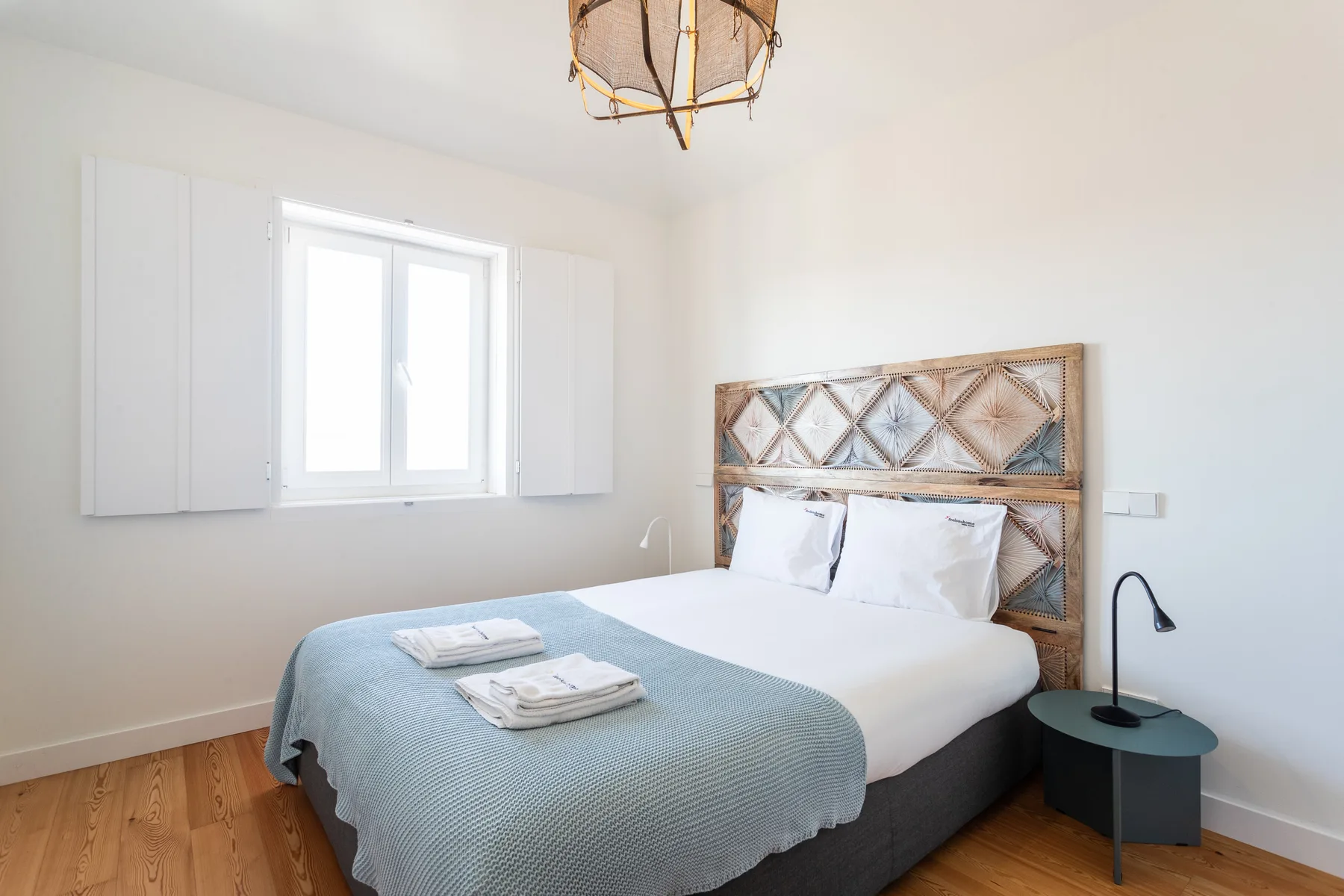 A bright bedroom with a bed dressed in pale blue bedding.
