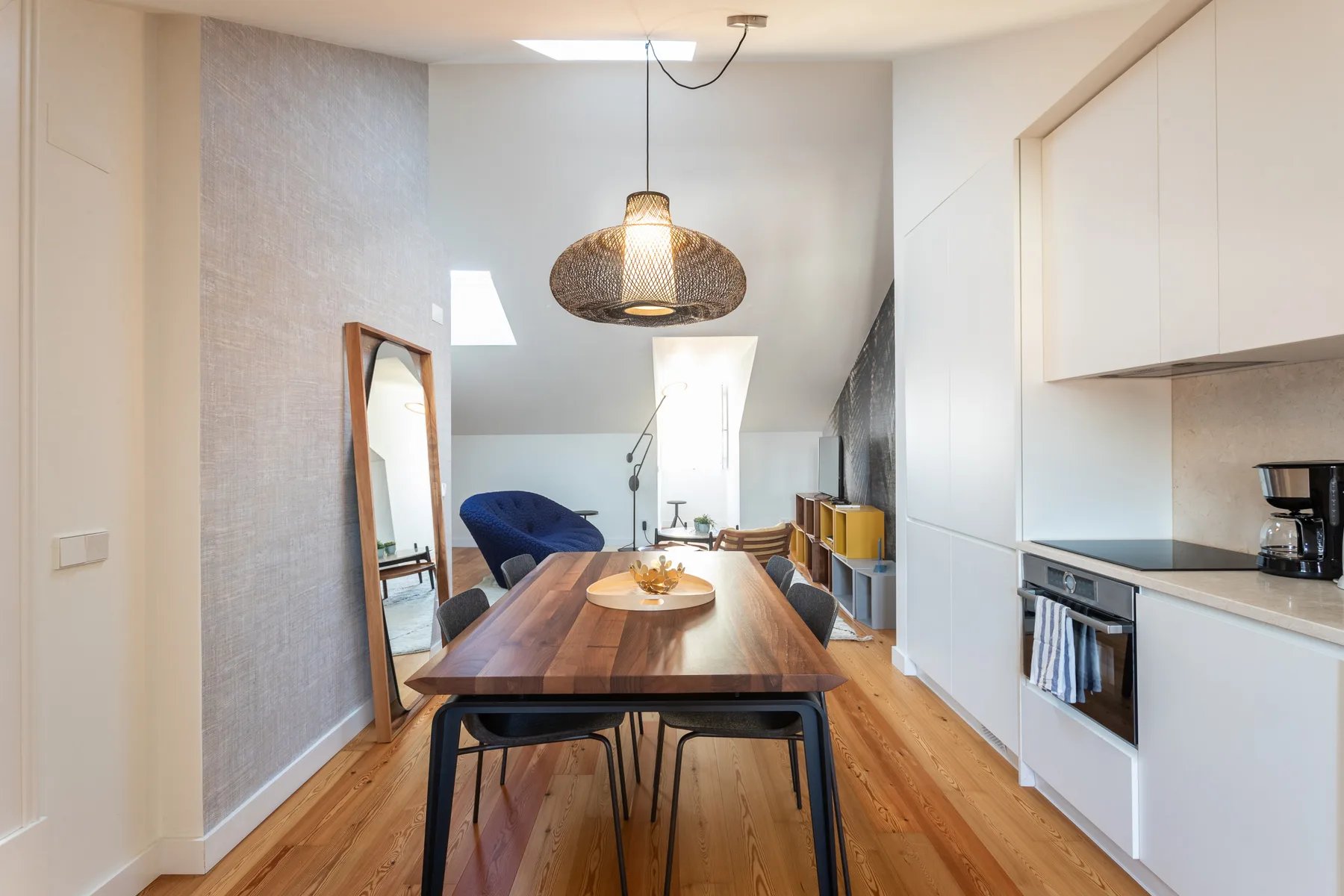 A dining area with a wooden table, chairs, and a hanging light.