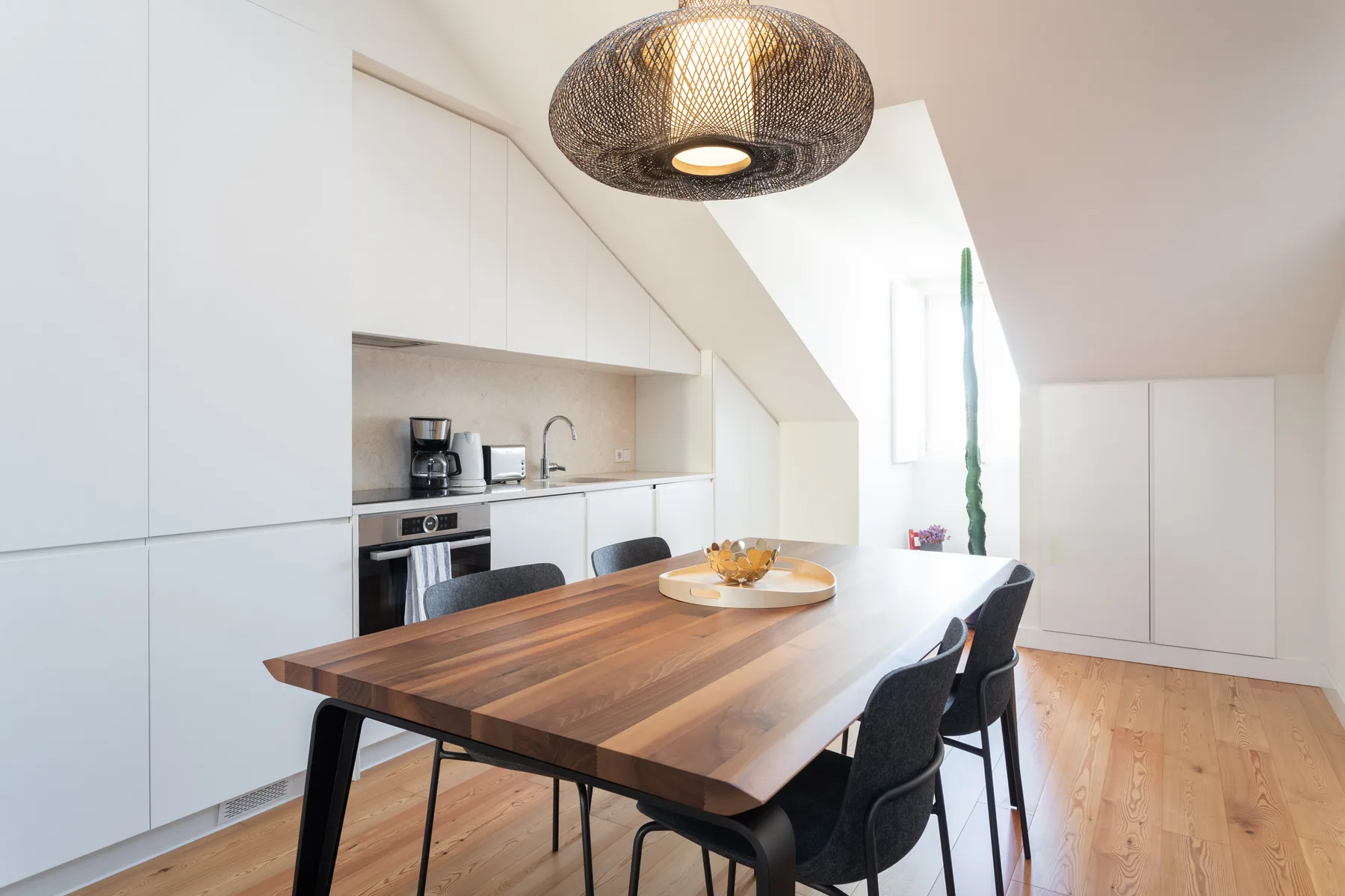 A dining area with a wooden table and chairs beneath a woven pendant light.