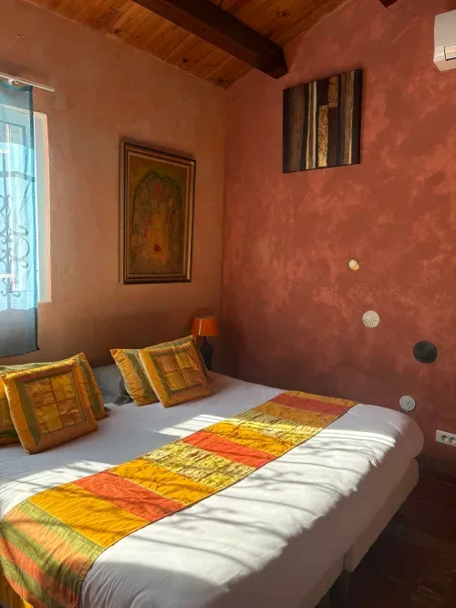 Bedroom with terracotta-colored walls and exposed wooden beams.