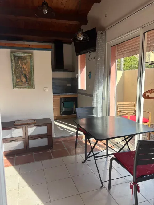 Dining area with kitchen, television and garden view.