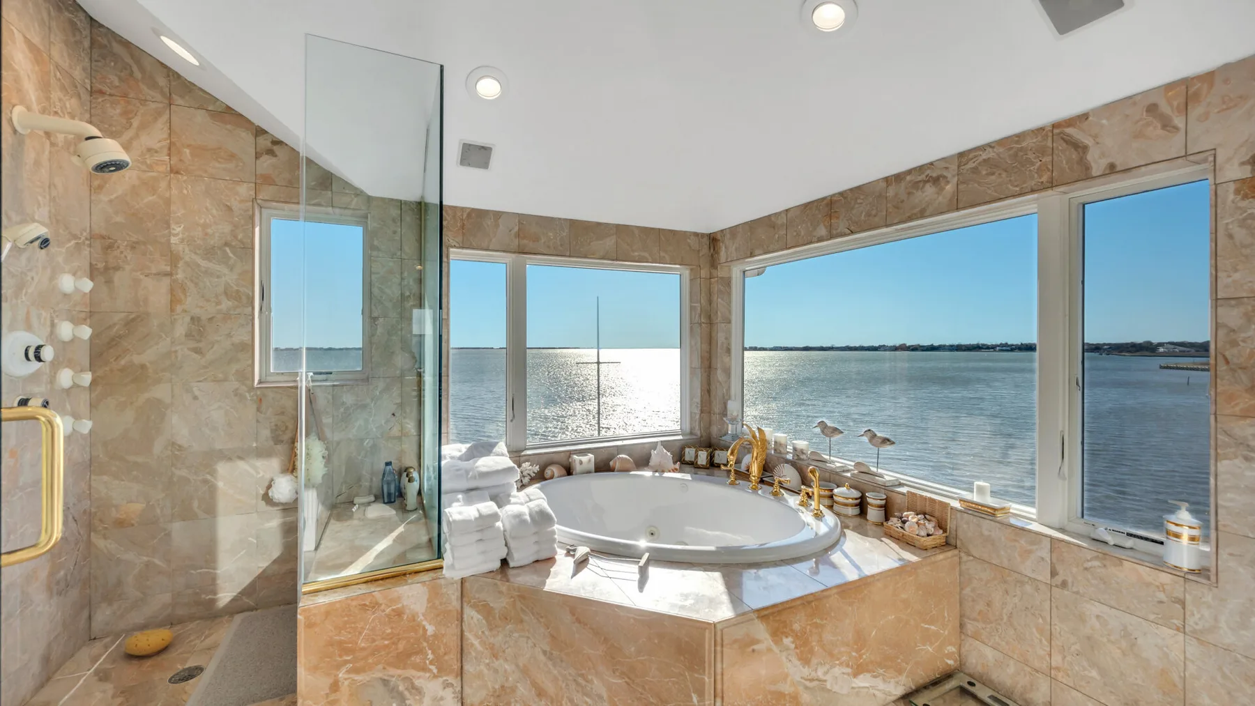 Un baño con una bañera integrada junto a grandes ventanas con vista al agua.