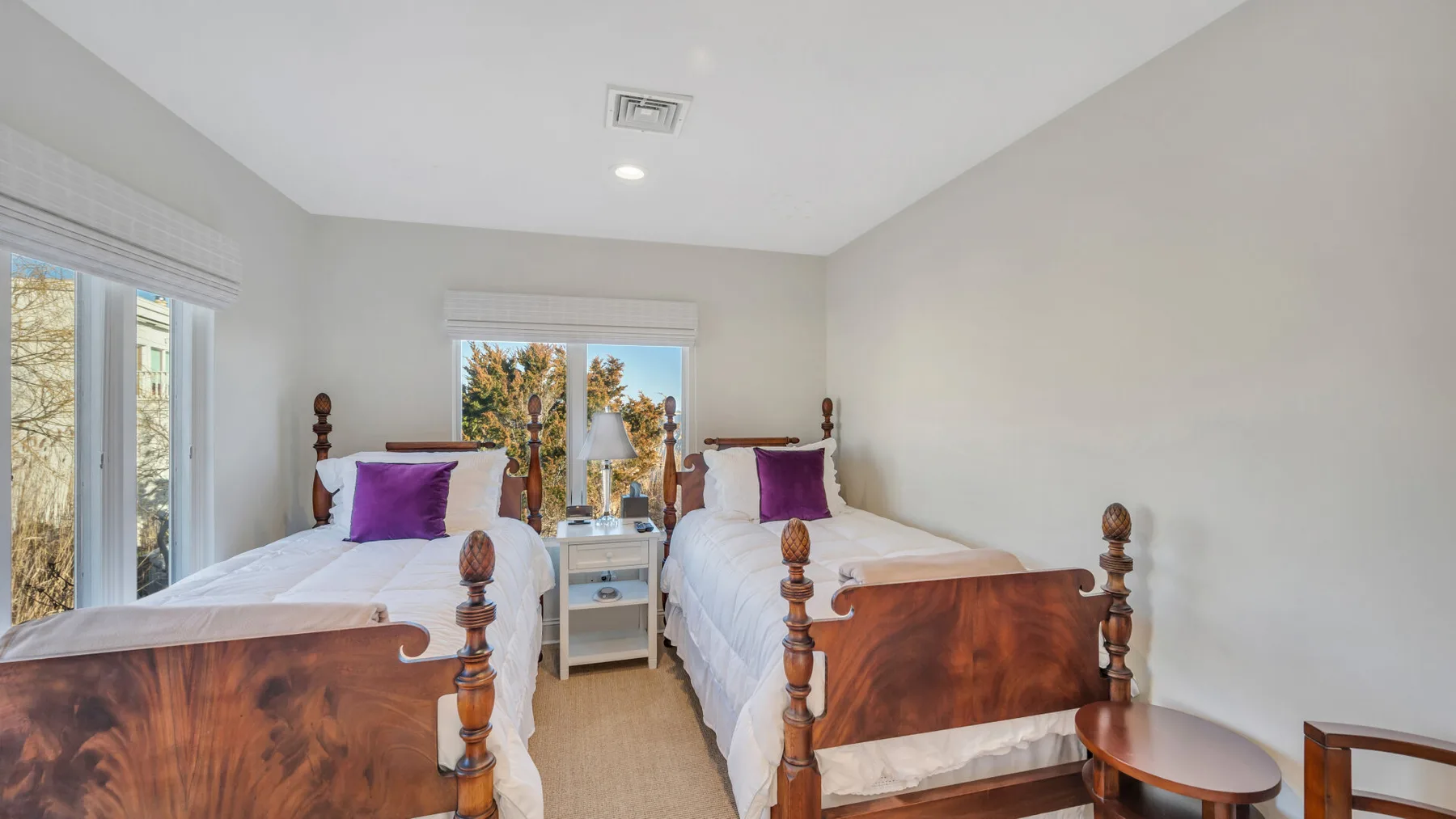 Un dormitorio luminoso con dos camas y una mesita entre ellas.