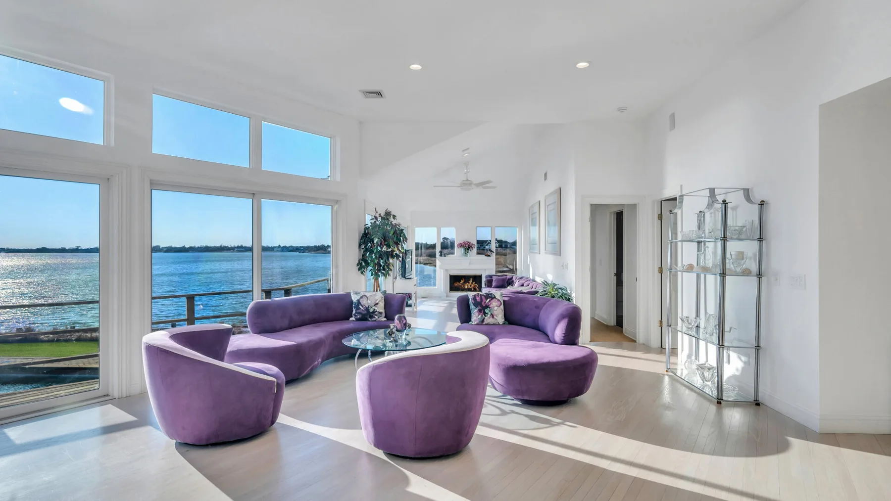 Una sala luminosa con asientos morados junto a grandes ventanas con vistas al agua.