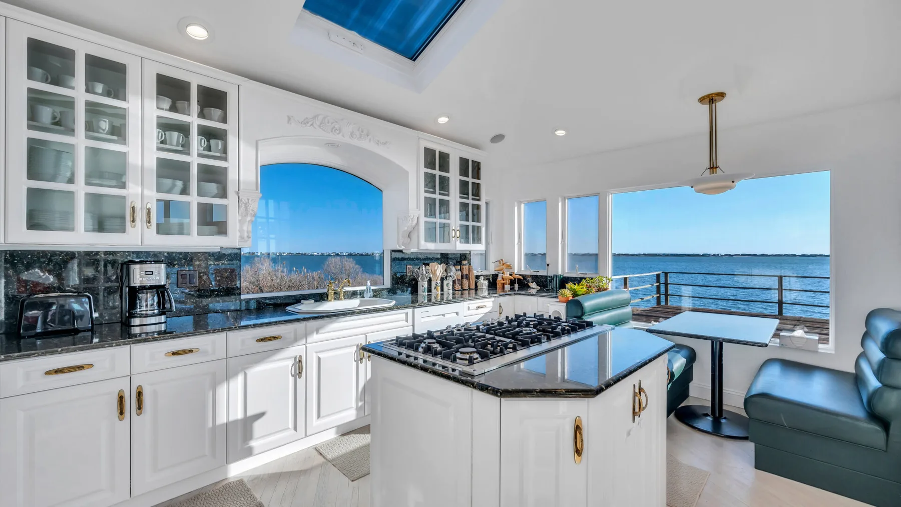 Una cocina luminosa con gabinetes blancos e isla central para cocinar da al agua.