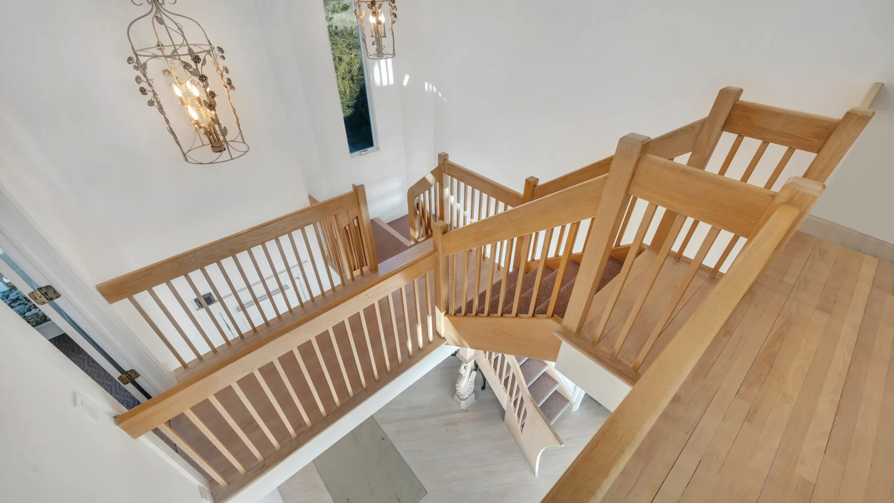Una escalera interior de madera con barandillas conecta los niveles de un espacio luminoso.