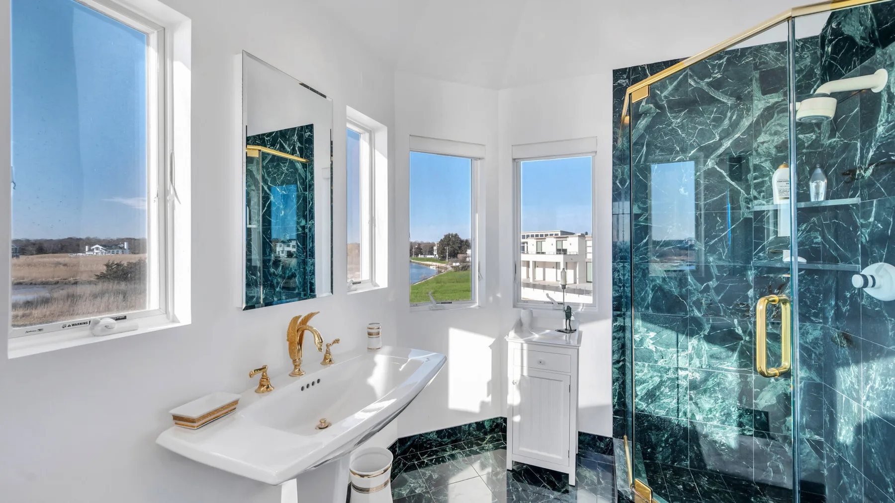 Un baño luminoso con un lavabo blanco y una ducha de vidrio.