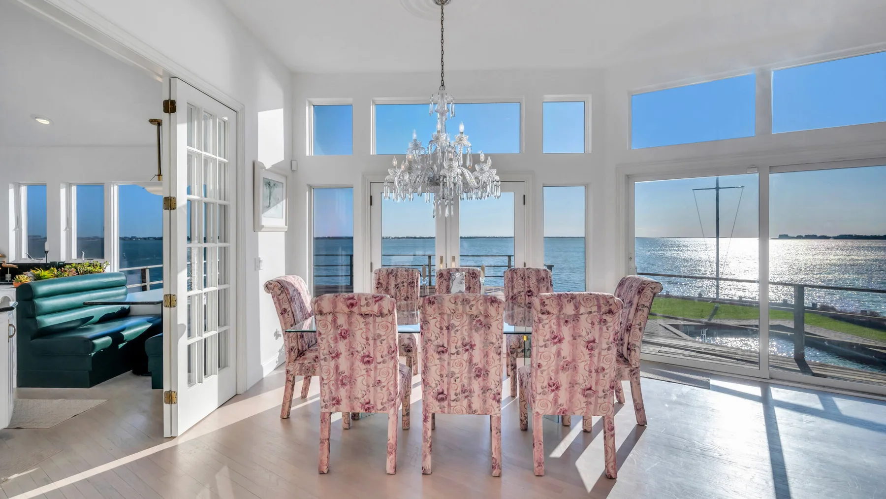 Un comedor luminoso con una mesa y asientos tapizados junto a grandes ventanas.
