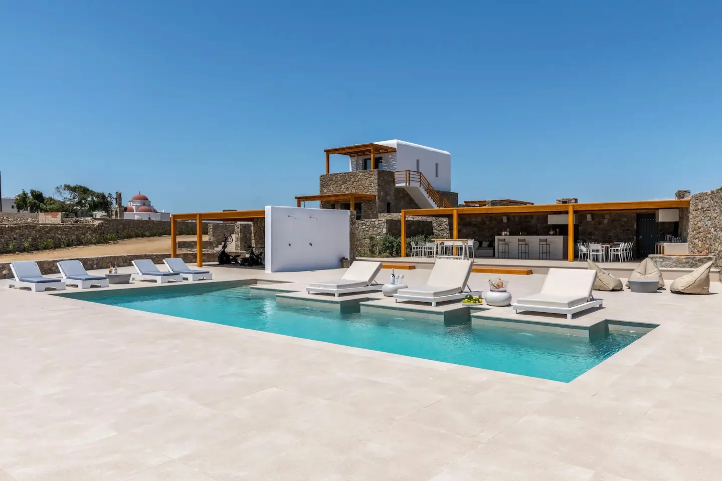 An outdoor pool with sun loungers beside a modern building.
