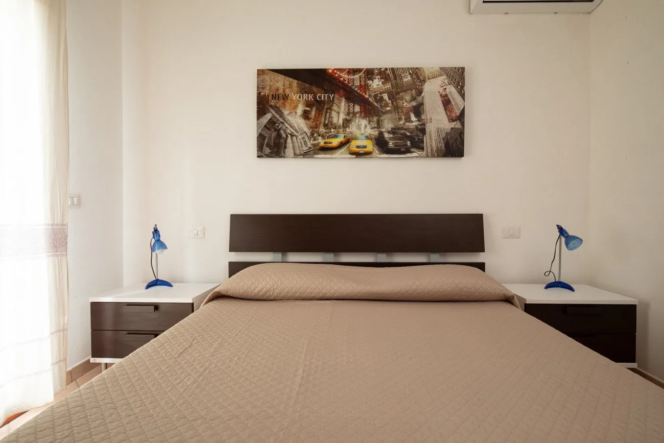 Un dormitorio con una cama grande, mesitas de noche a juego y un cuadro.