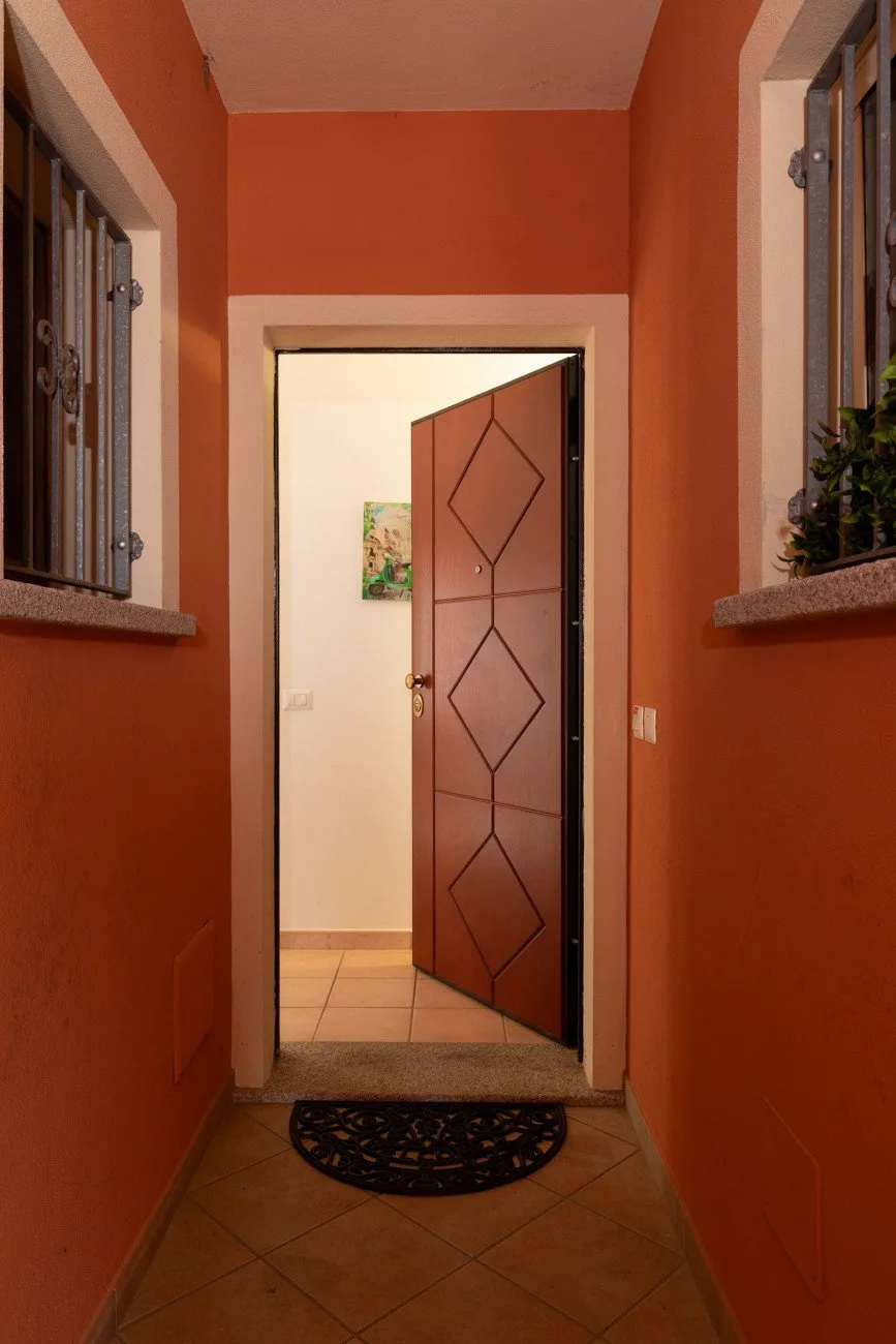 Un pasillo de entrada naranja conduce a una puerta abierta con diseños geométricos.