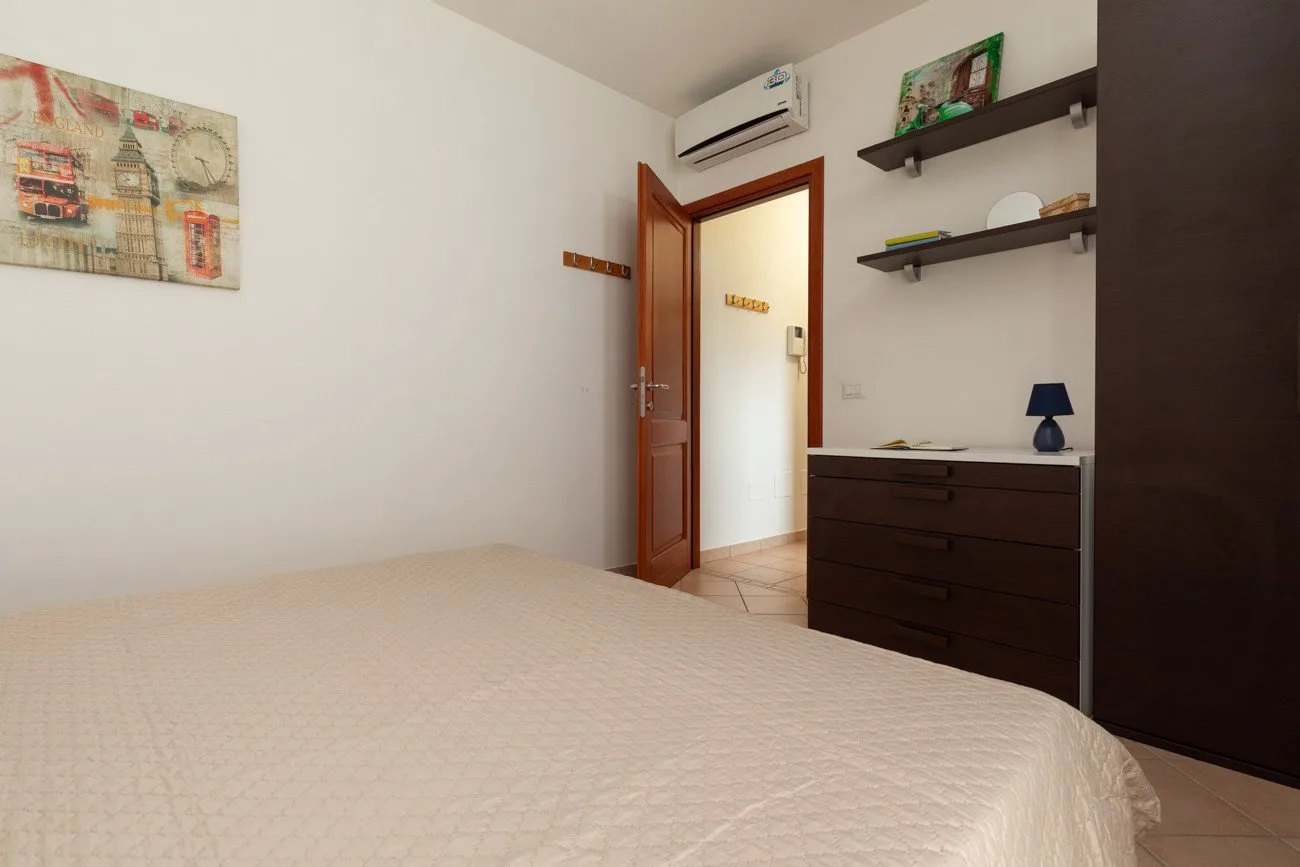 Un dormitorio con una cama, una puerta abierta y una cómoda oscura.