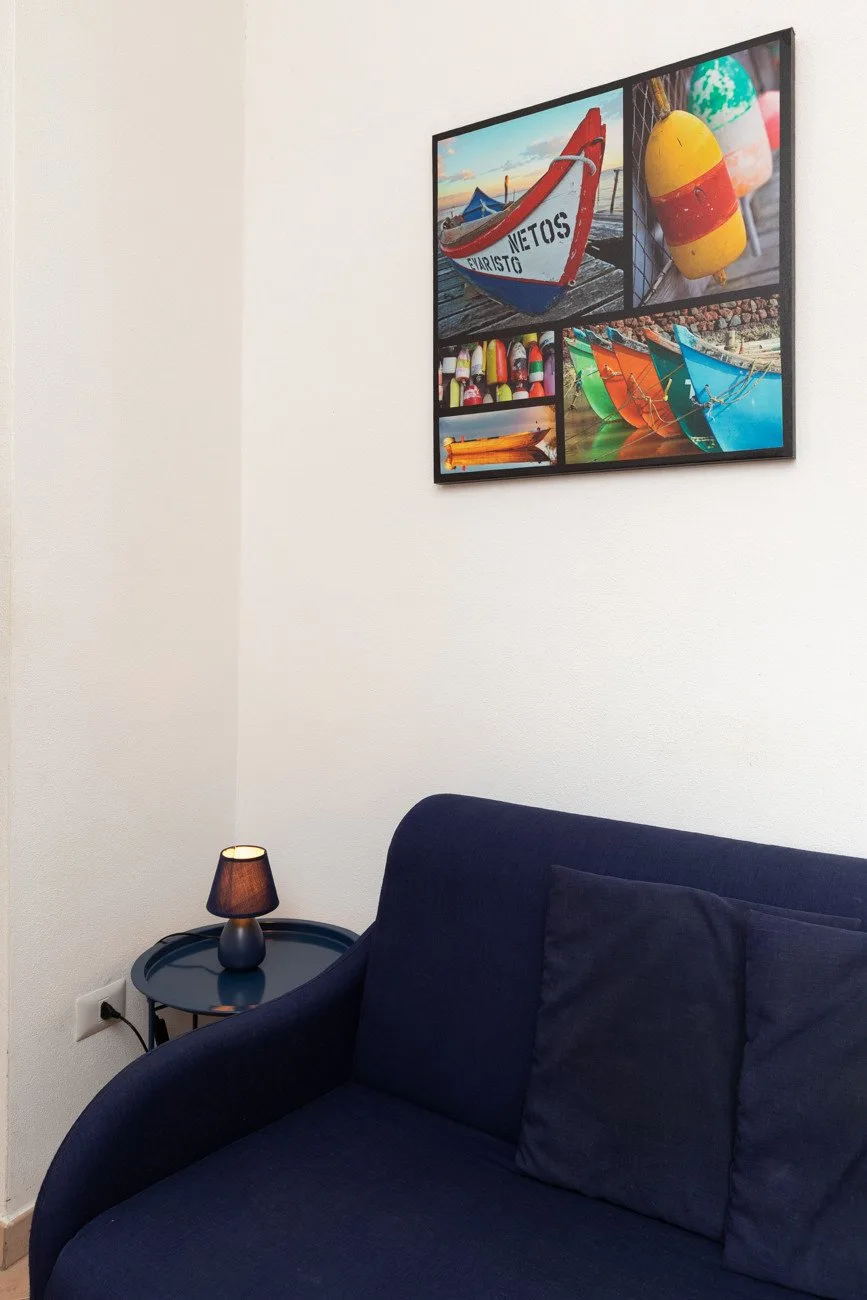 Una zona de asientos azul marino está bajo un collage colorido enmarcado en una pared blanca.
