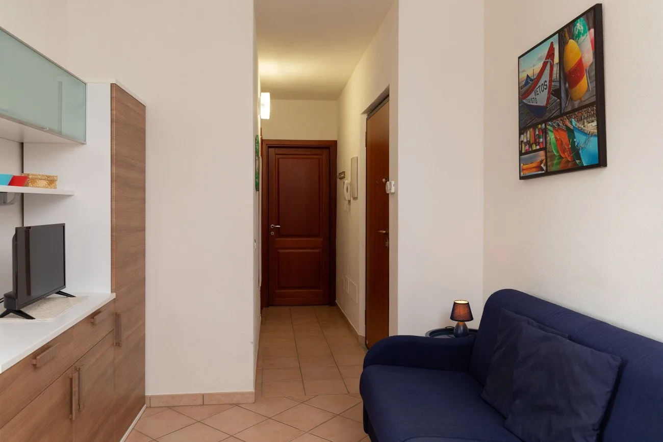 Un pasillo con una puerta de madera pasa junto a un sofá azul y arte mural.