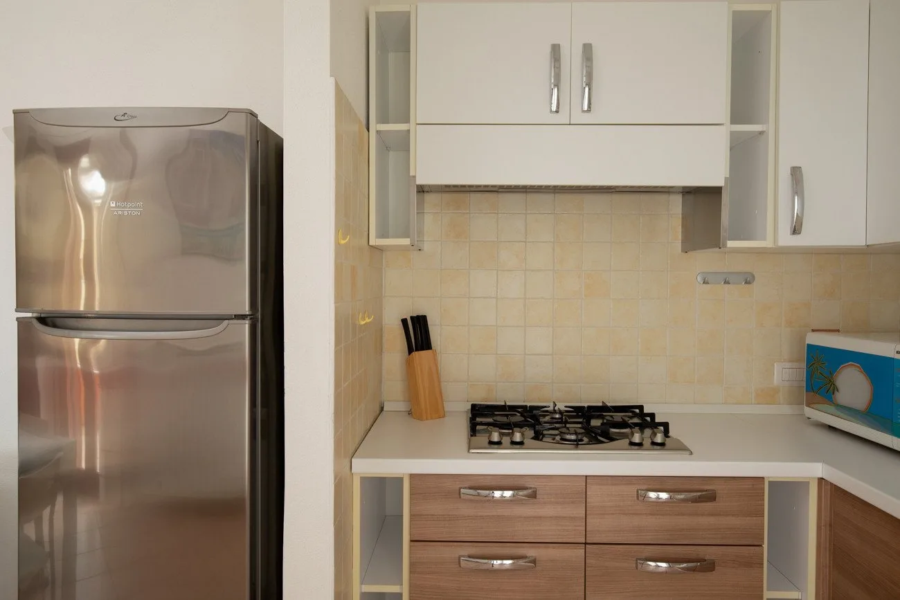 Una cocina con una estufa de gas, armarios y un refrigerador.