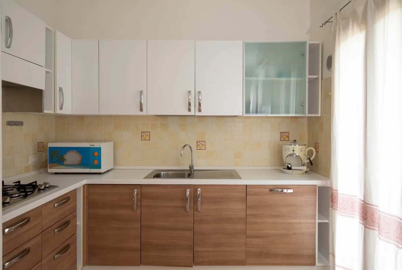 Una cocina compacta con gabinetes de madera, fregadero y placa de cocción.