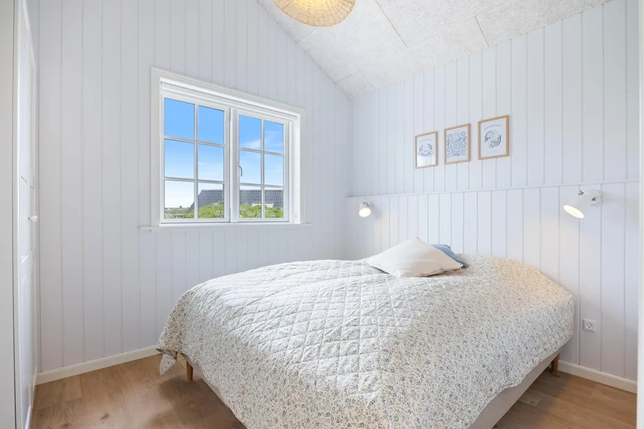 Un dormitorio luminoso con una cama junto a una ventana.