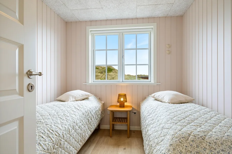 Un dormitorio pequeño con dos camas y una ventana con vistas a la vegetación.