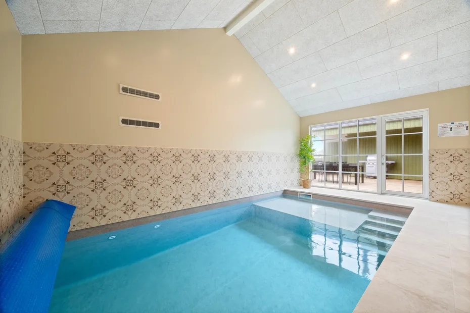 Una piscina cubierta con paredes de azulejos y puertas de vidrio.