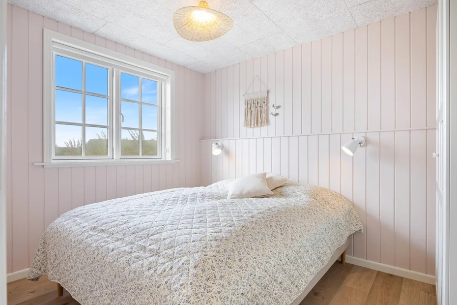 Un dormitorio con una cama debajo de una ventana.