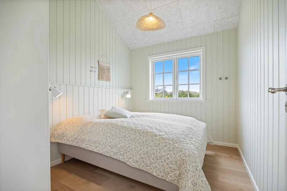 Un dormitorio luminoso con una cama bajo una ventana.