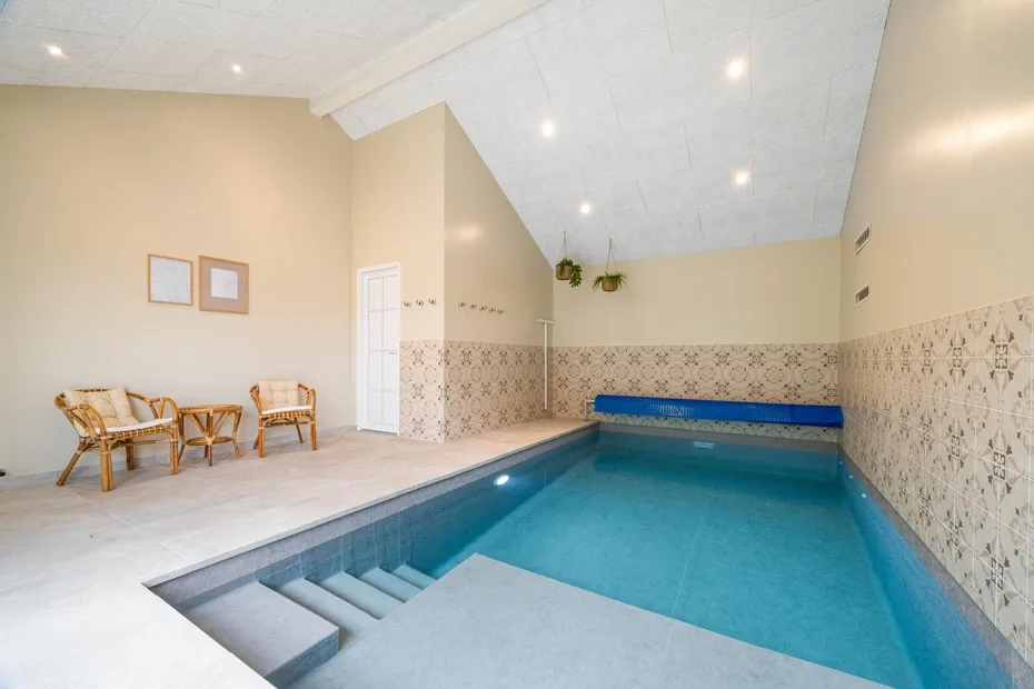Una piscina cubierta con paredes alicatadas y asientos a un lado.