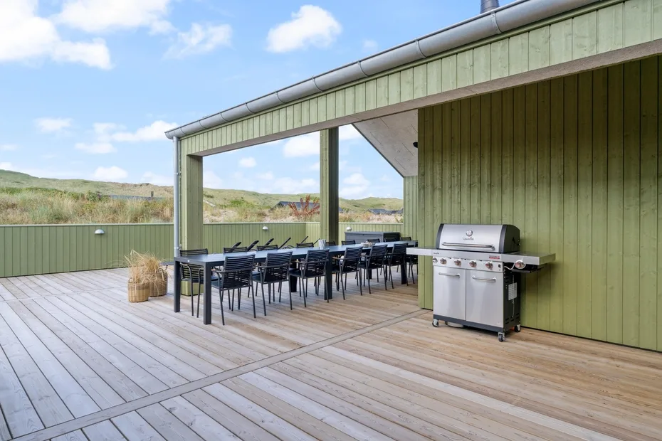 Comedor exterior cubierto con mesa, sillas y parrilla.