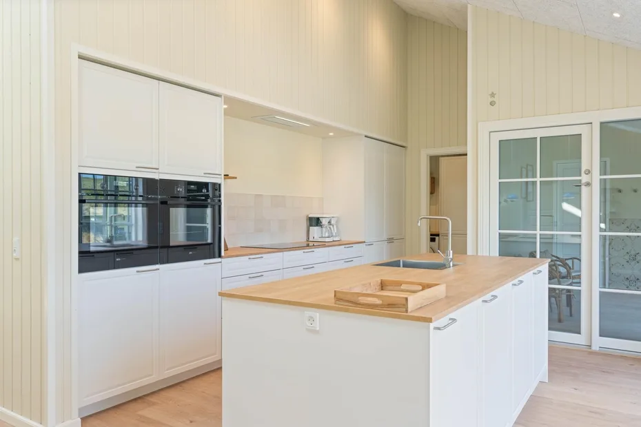 Una cocina luminosa con gabinetes blancos e isla central.