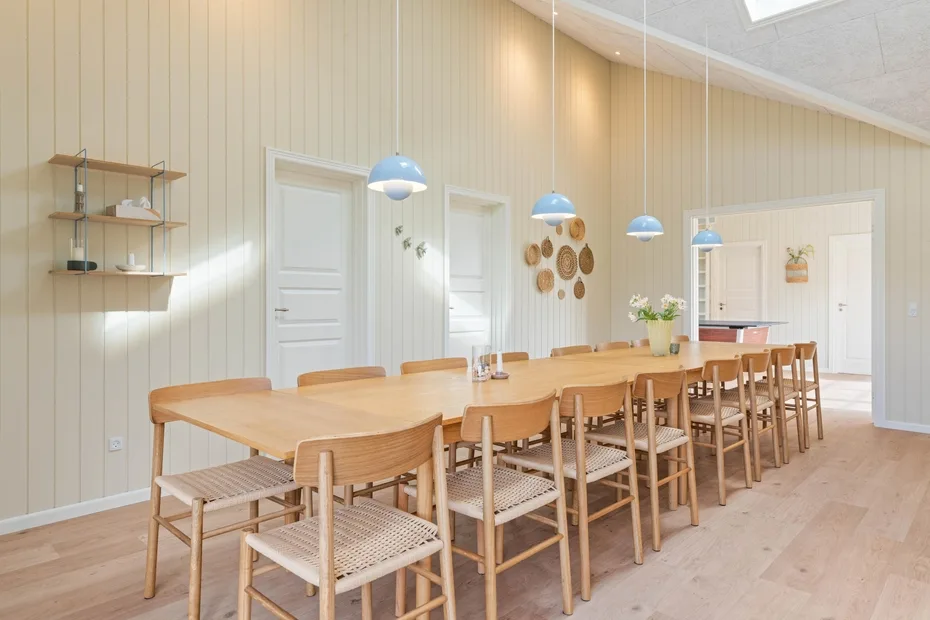 Un comedor luminoso con una larga mesa de madera y asientos dispuestos en fila.