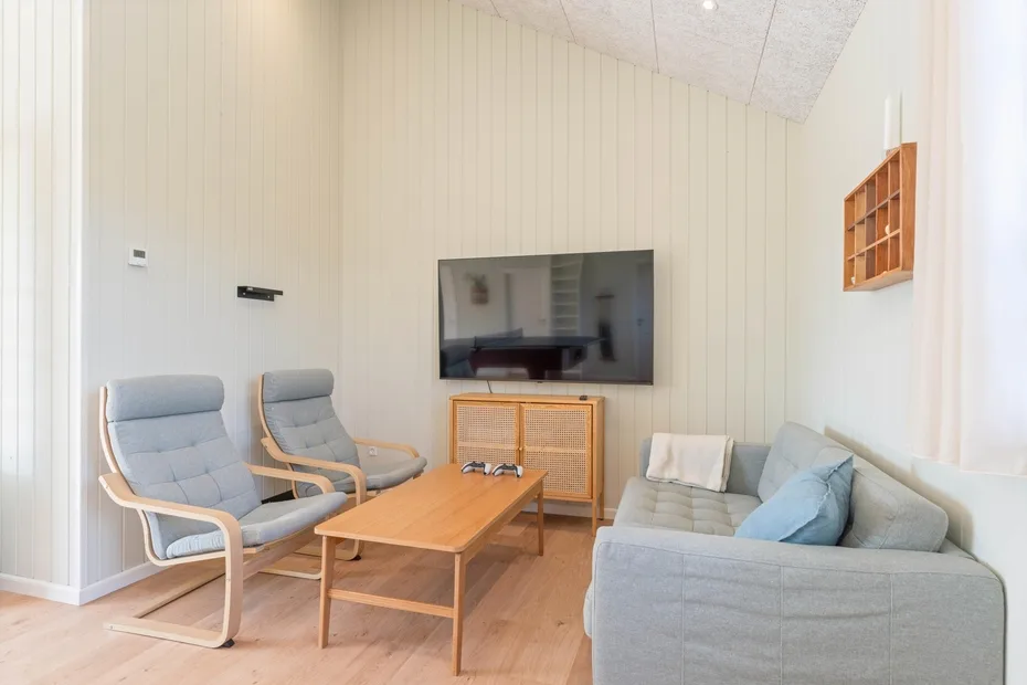 Una sala de estar luminosa con televisor, mesa de centro y asientos.
