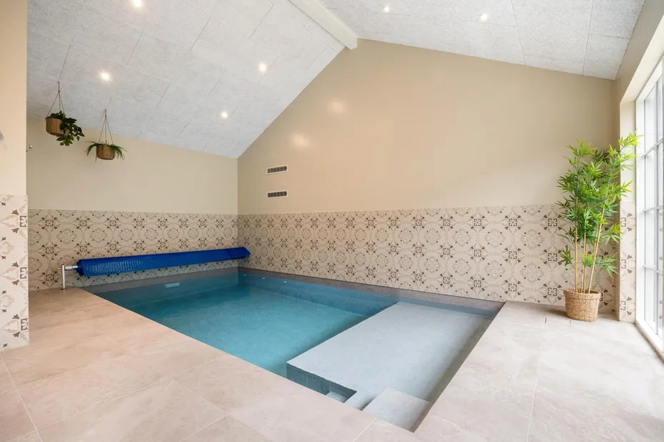 Una piscina cubierta con paredes revestidas de azulejos y una zona poco profunda.