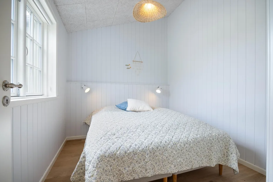 Un dormitorio luminoso con una cama bajo dos luces de pared.