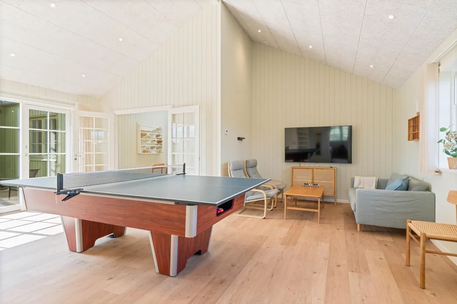 Una luminosa sala recreativa tiene una mesa de ping-pong y una zona de asientos.