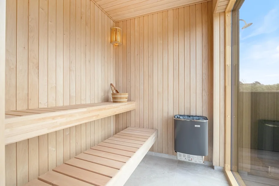 Una sauna revestida de madera con asientos escalonados y un calentador.