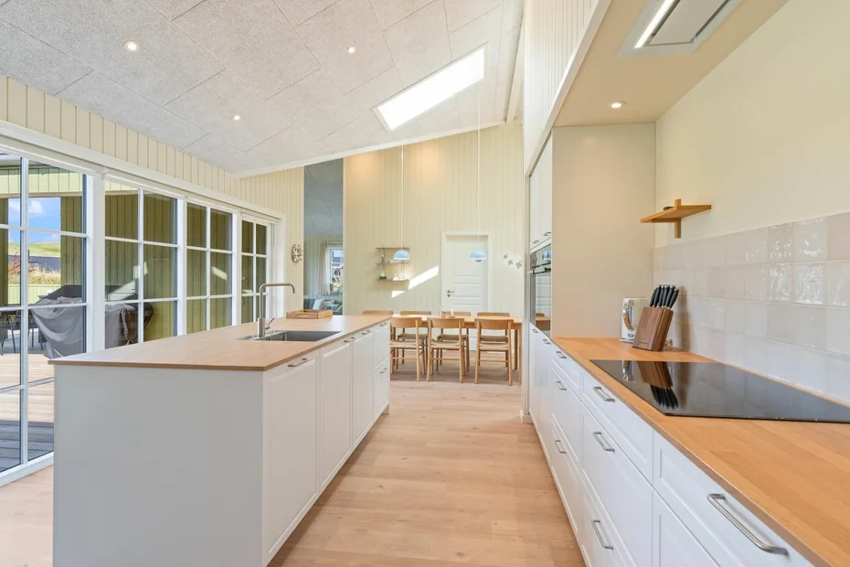 Una cocina luminosa con una isla central y una mesa de comedor al fondo.