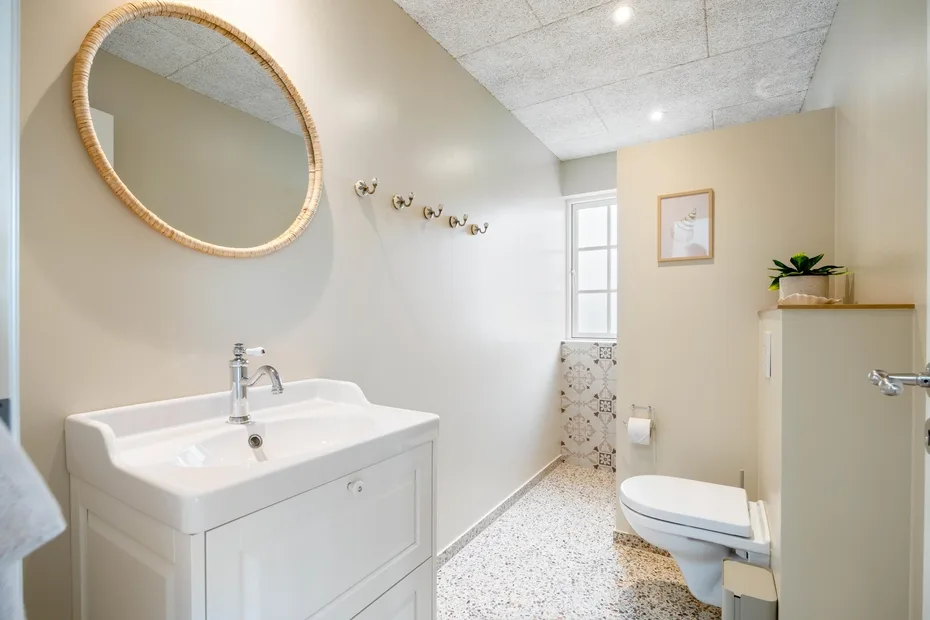 Un baño luminoso con un lavabo amplio, un espejo de pared y un inodoro.