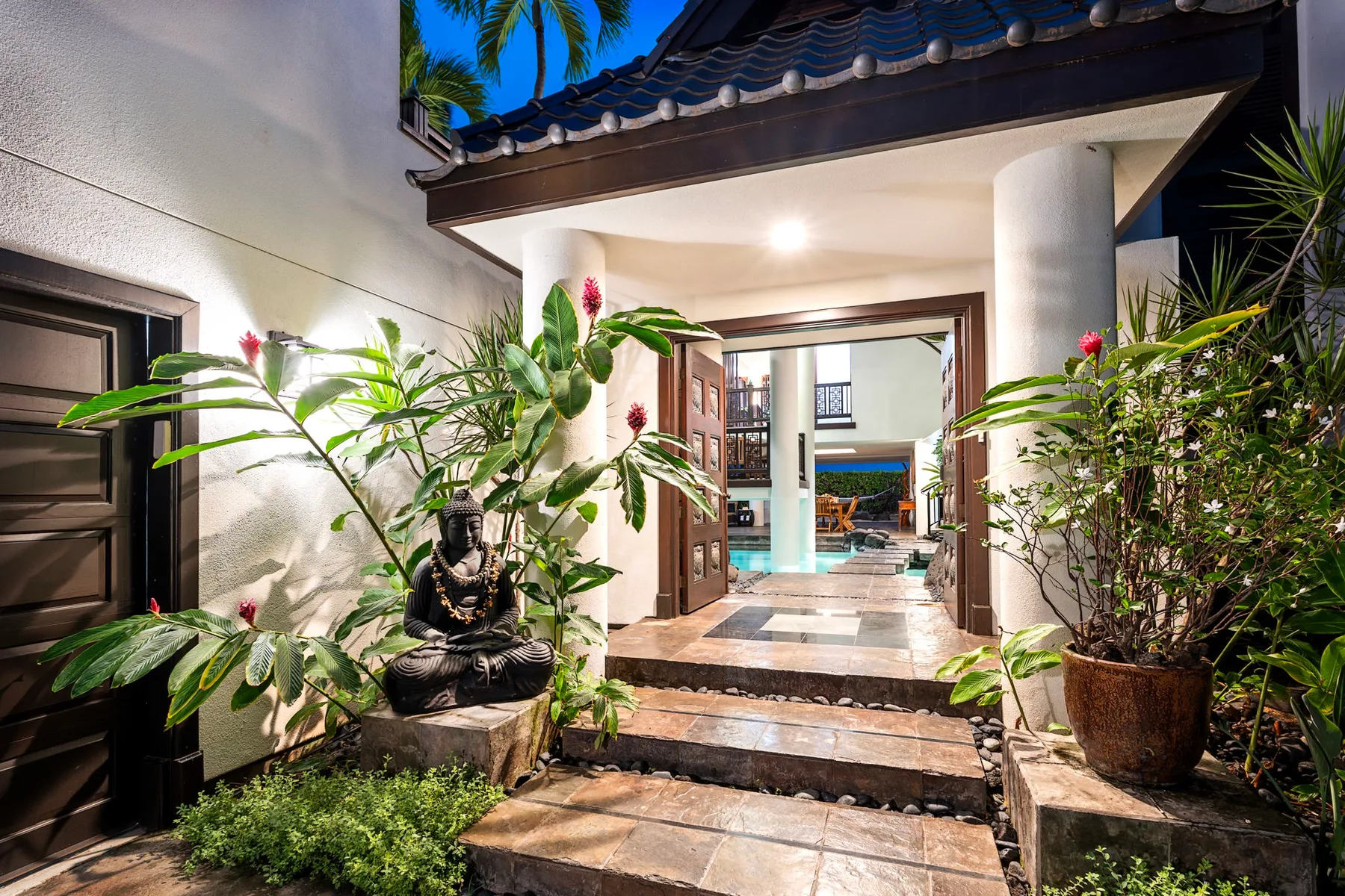 Una entrada abierta conduce a un interior luminoso, con plantas en macetas junto al paso.