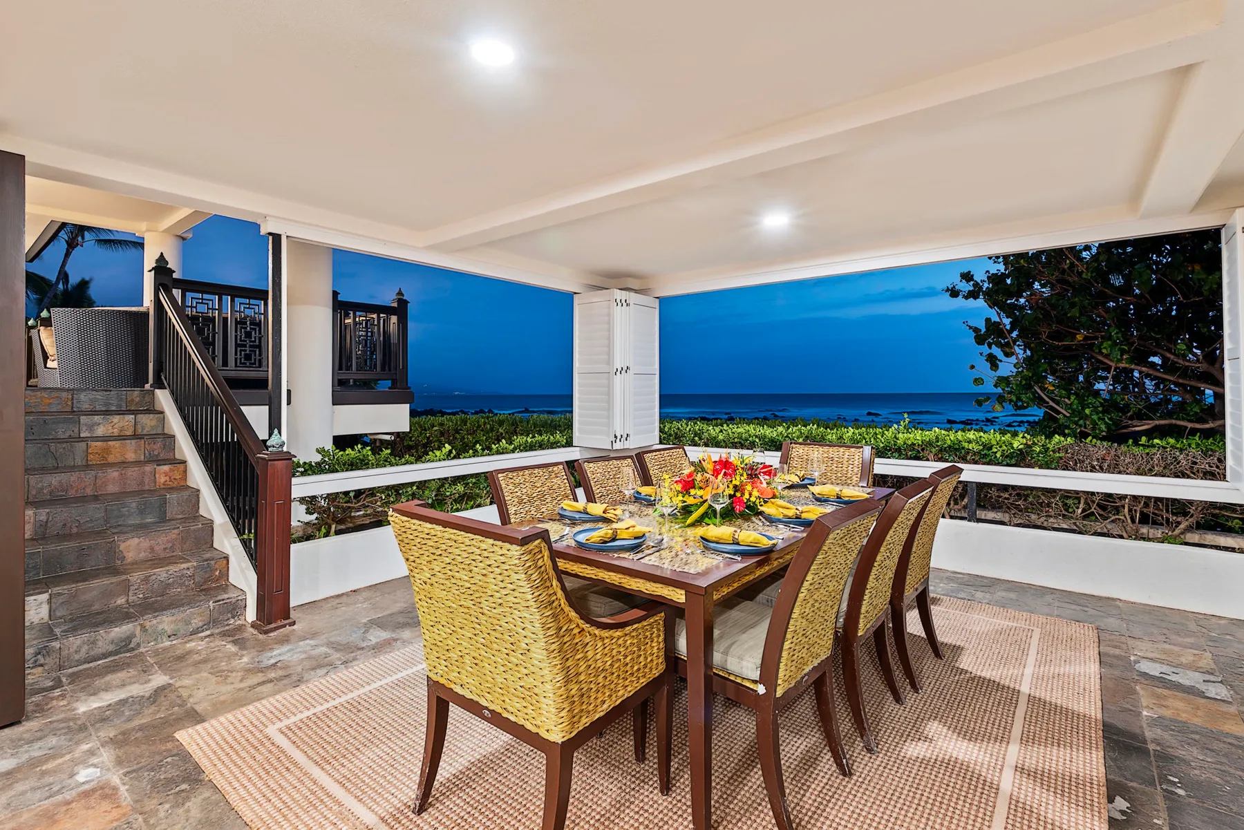 Un comedor exterior cubierto da al mar, con una mesa preparada para comer.